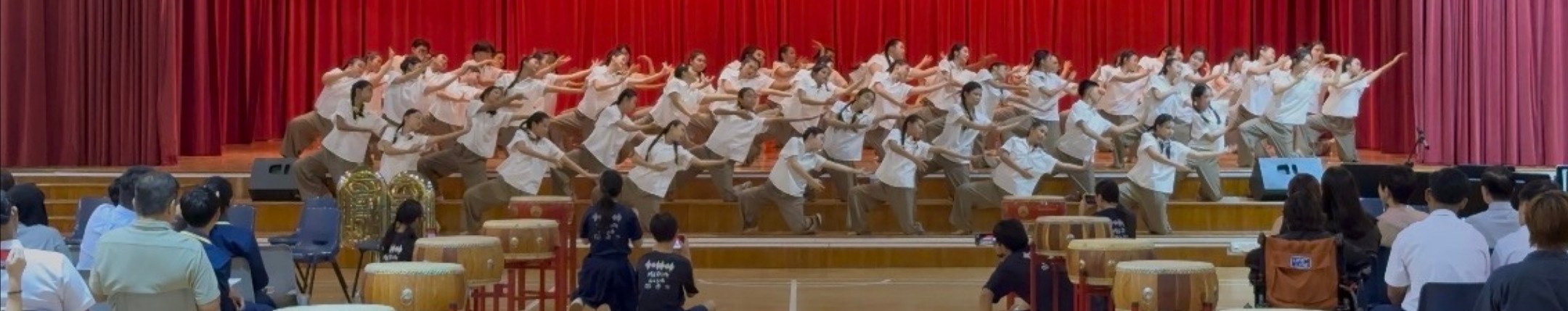 School dance ensemble performing on a stage with red curtains
